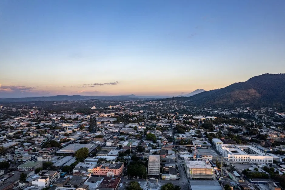 Panoramic aerial view of San Salvador cityscape at sunset with mountains in the background.