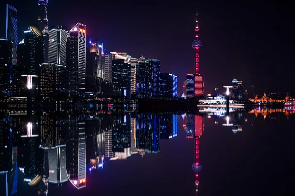 Dazzling night view of Shanghai's Pudong skyline with the iconic Oriental Pearl Tower reflecting on the water.