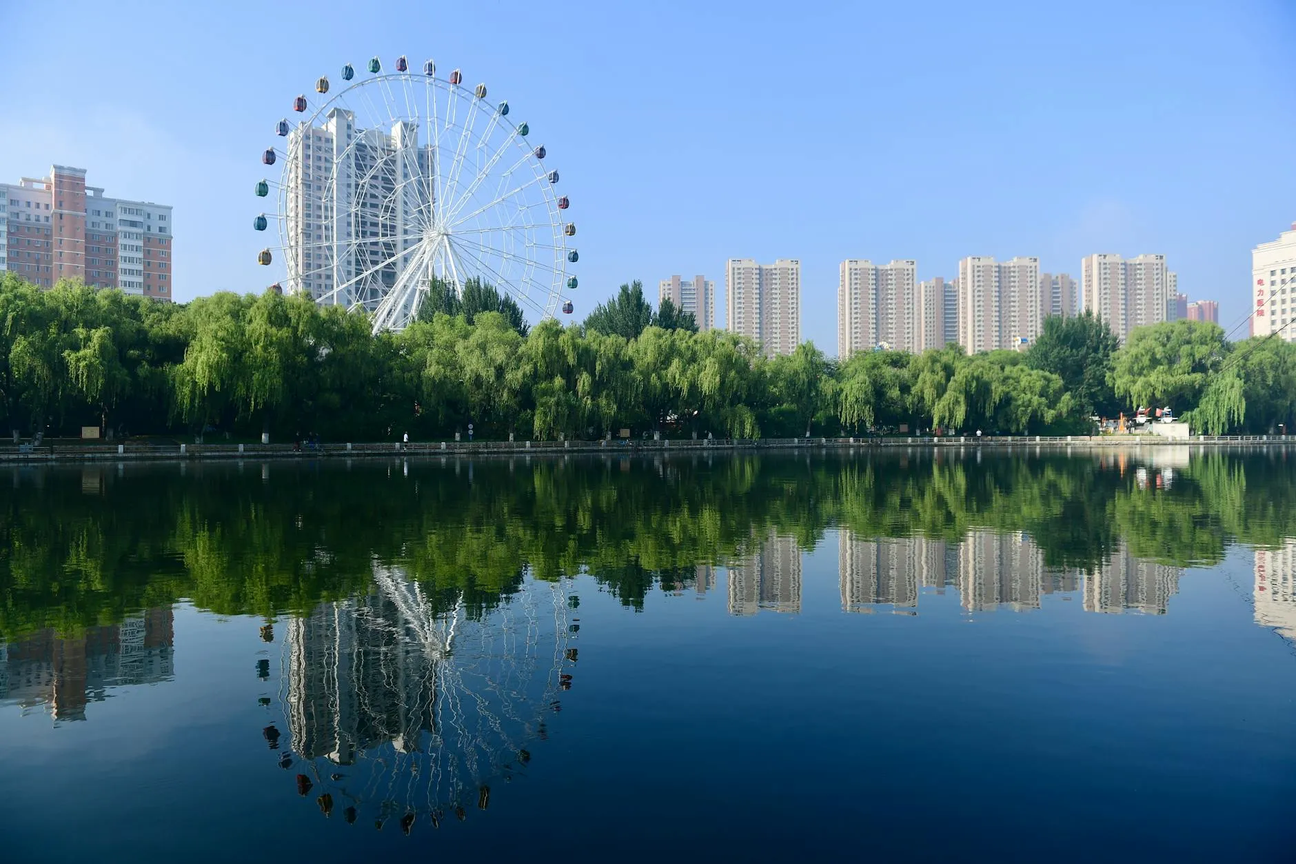 Shenyang, China — Scenic view of Ferris wheel and urban skyline reflecting in a lake in Shenyang, China.