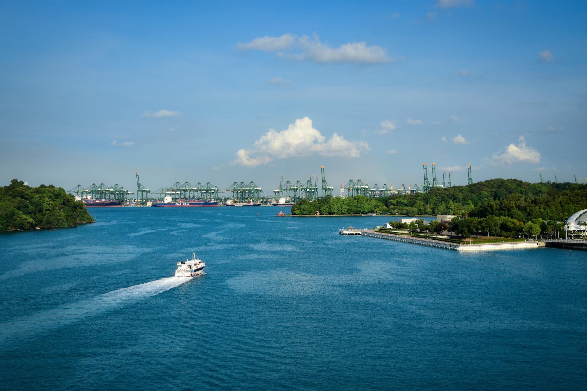 Stunning aerial view of Singapore's bustling harbor and green cranes against a clear blue sky.