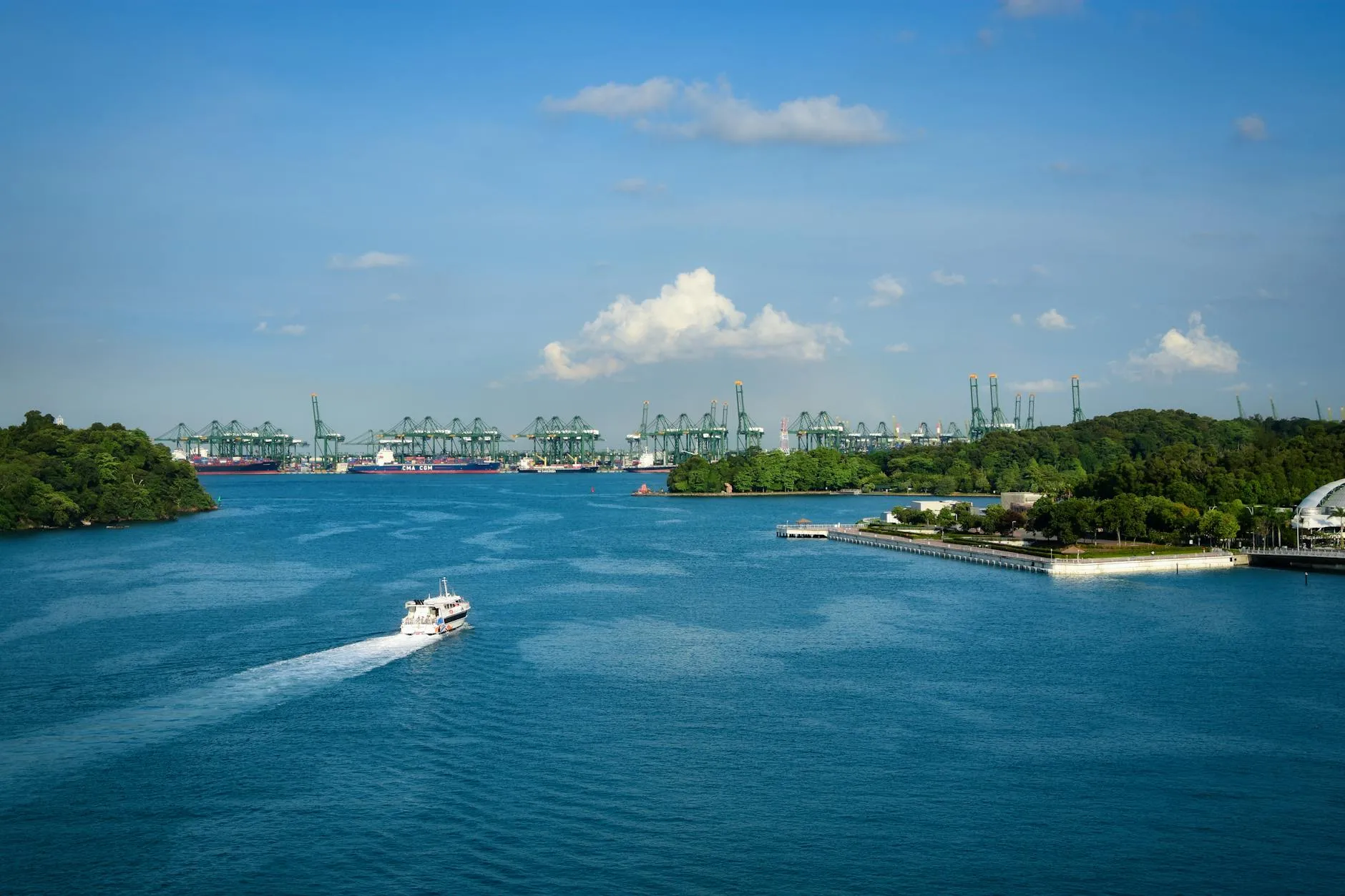 Stunning aerial view of Singapore's bustling harbor and green cranes against a clear blue sky.
