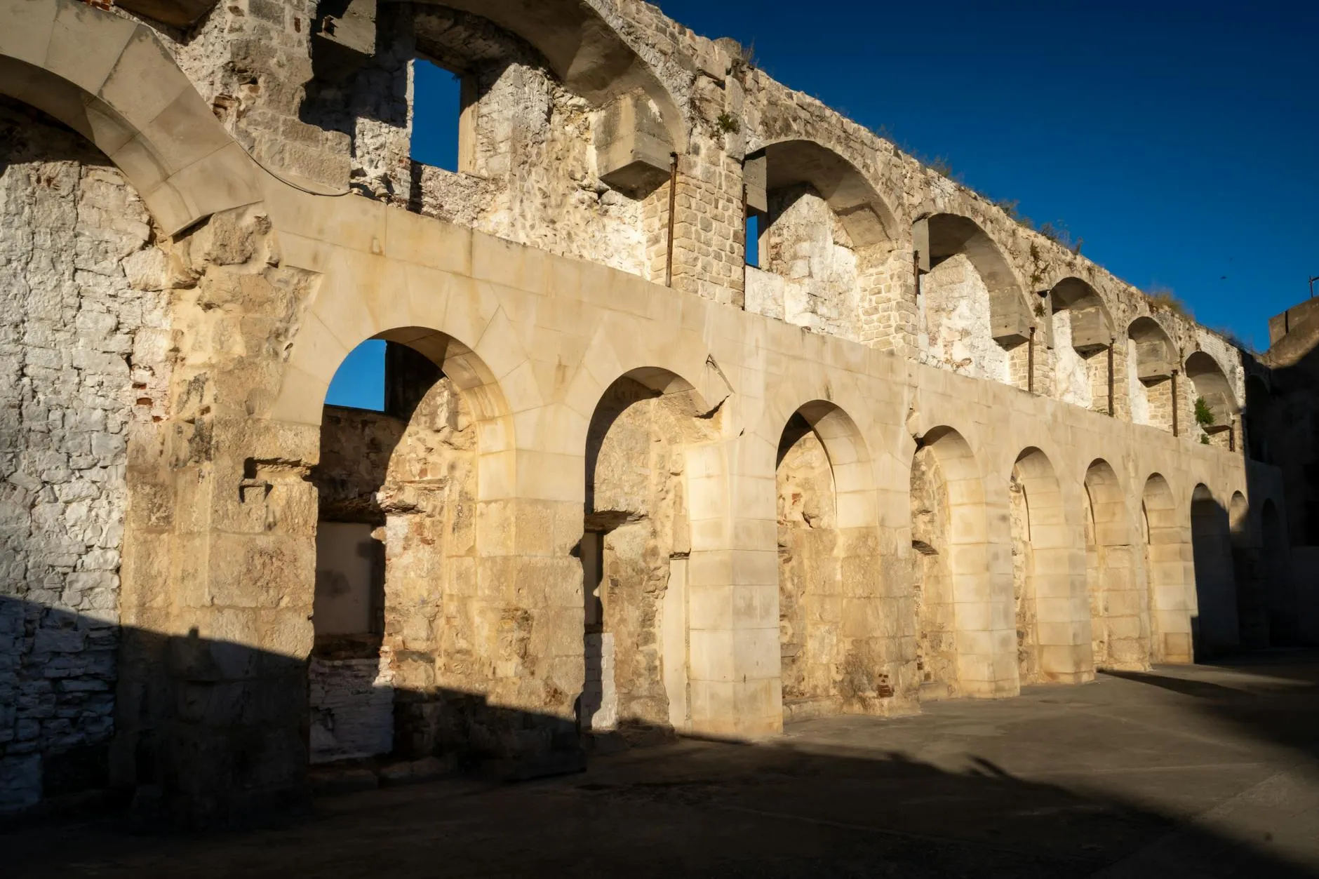 Sunlit Roman architectural ruins in Split, showcasing ancient arches and stonework.