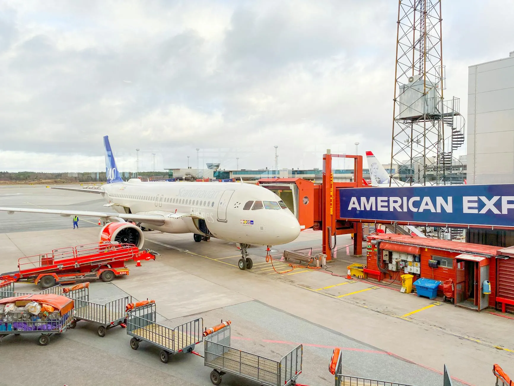 Aircraft docked at Stockholm Arlanda Airport gate with ground crew and equipment.