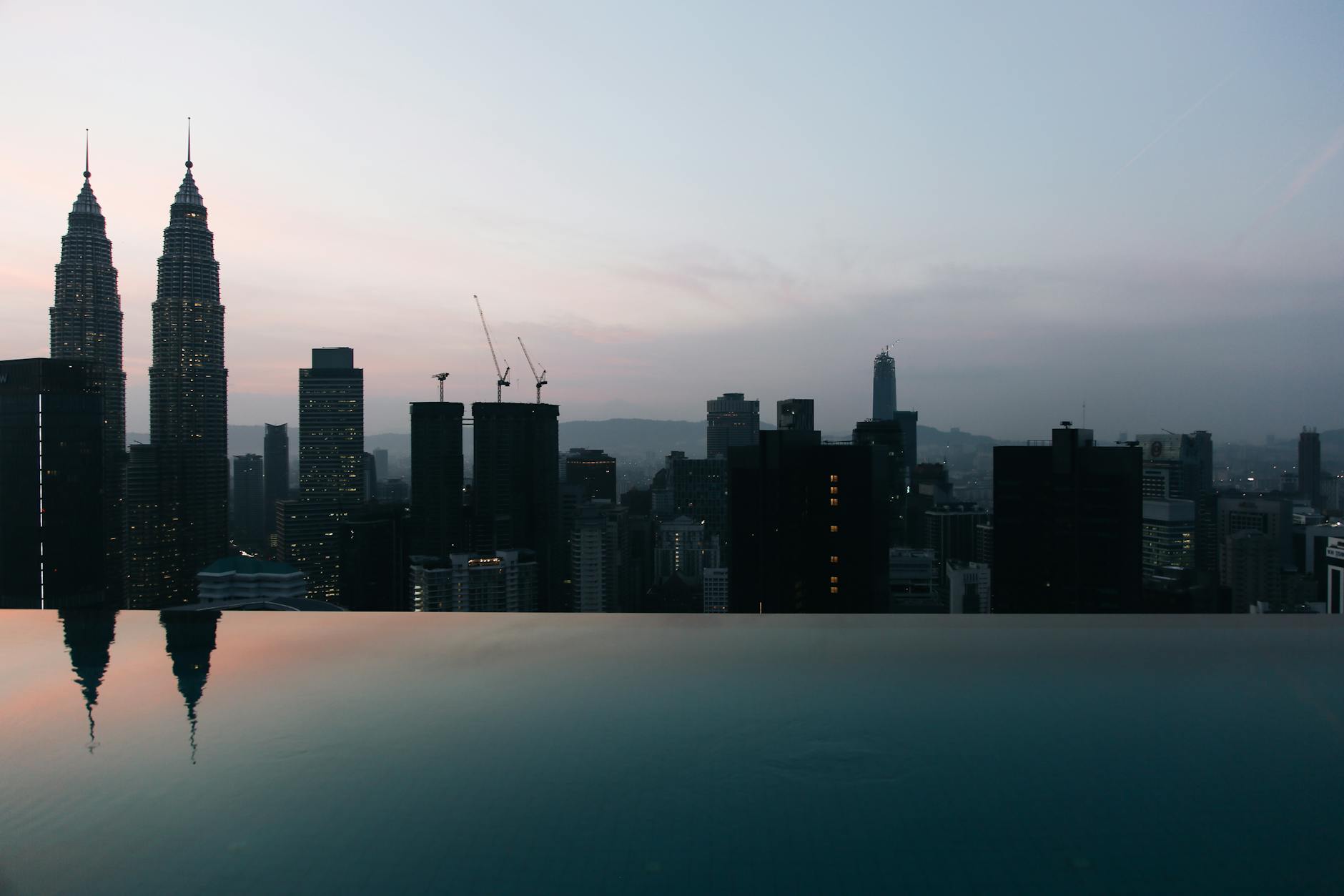 Subang, Kuala Lumpur, Malaysia — Twilight view of Kuala Lumpur skyline featuring the iconic Petronas Twin Towers reflecting in an infinity pool.