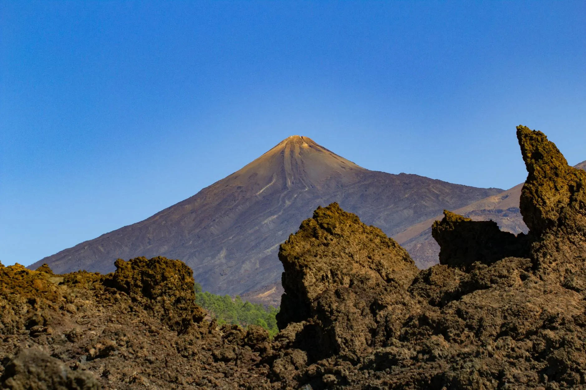 Stunning view of Mount Teide with rugged volcanic terrain under a clear blue sky.