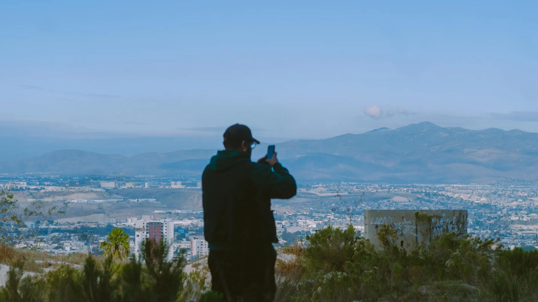 Tijuana, Mexico — A man captures a stunning mountain and cityscape view in Tijuana, Mexico, showcasing adventure and exploration.