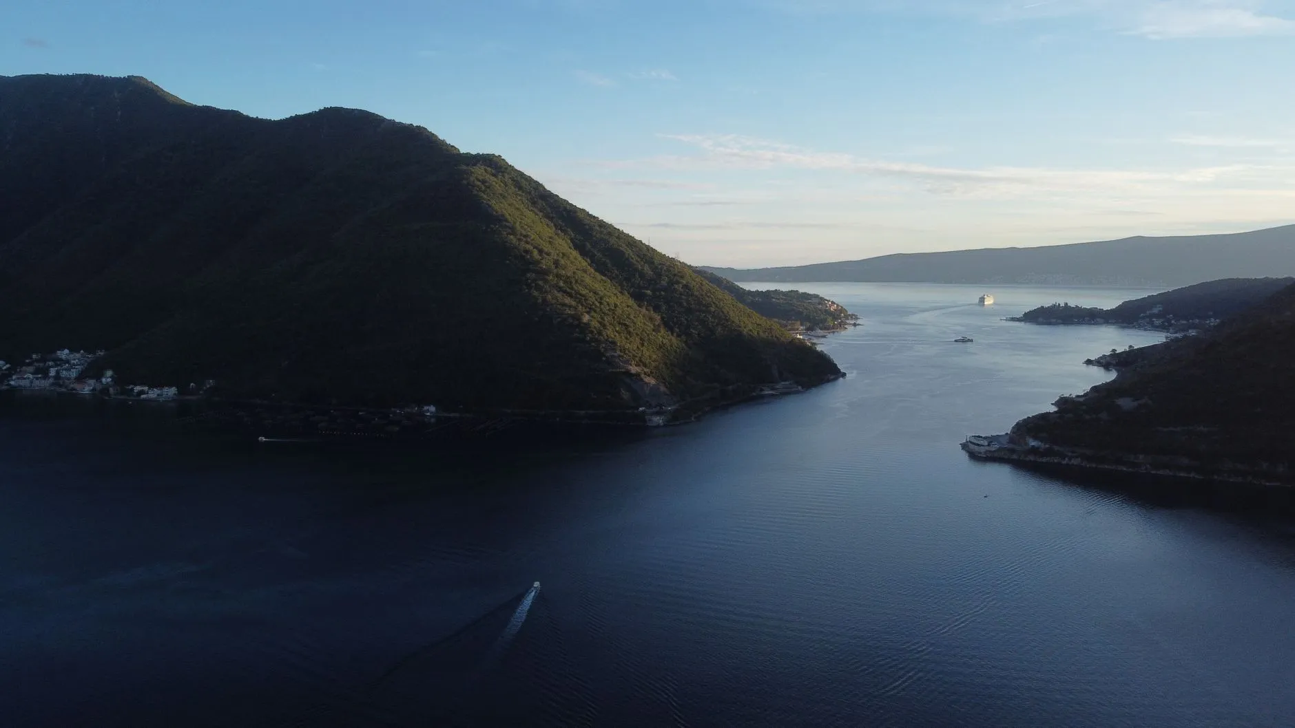 Tivat Airport (TIV) — A breathtaking aerial view of Perast Bay, Montenegro with mountains, sea, and a cruise ship at sunset.