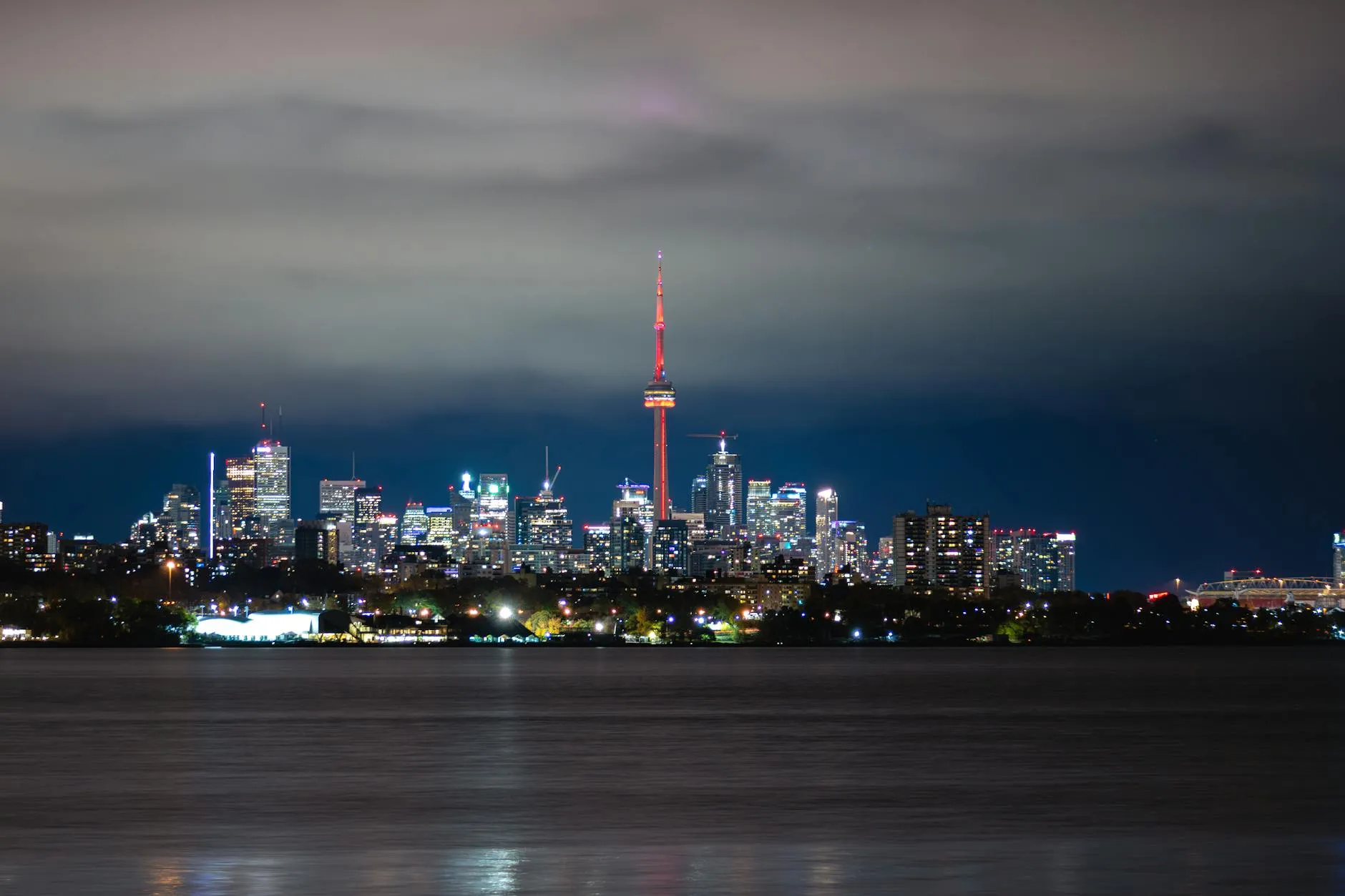 Breathtaking night view of Toronto cityscape with the iconic CN Tower glowing amidst the skyscrapers.