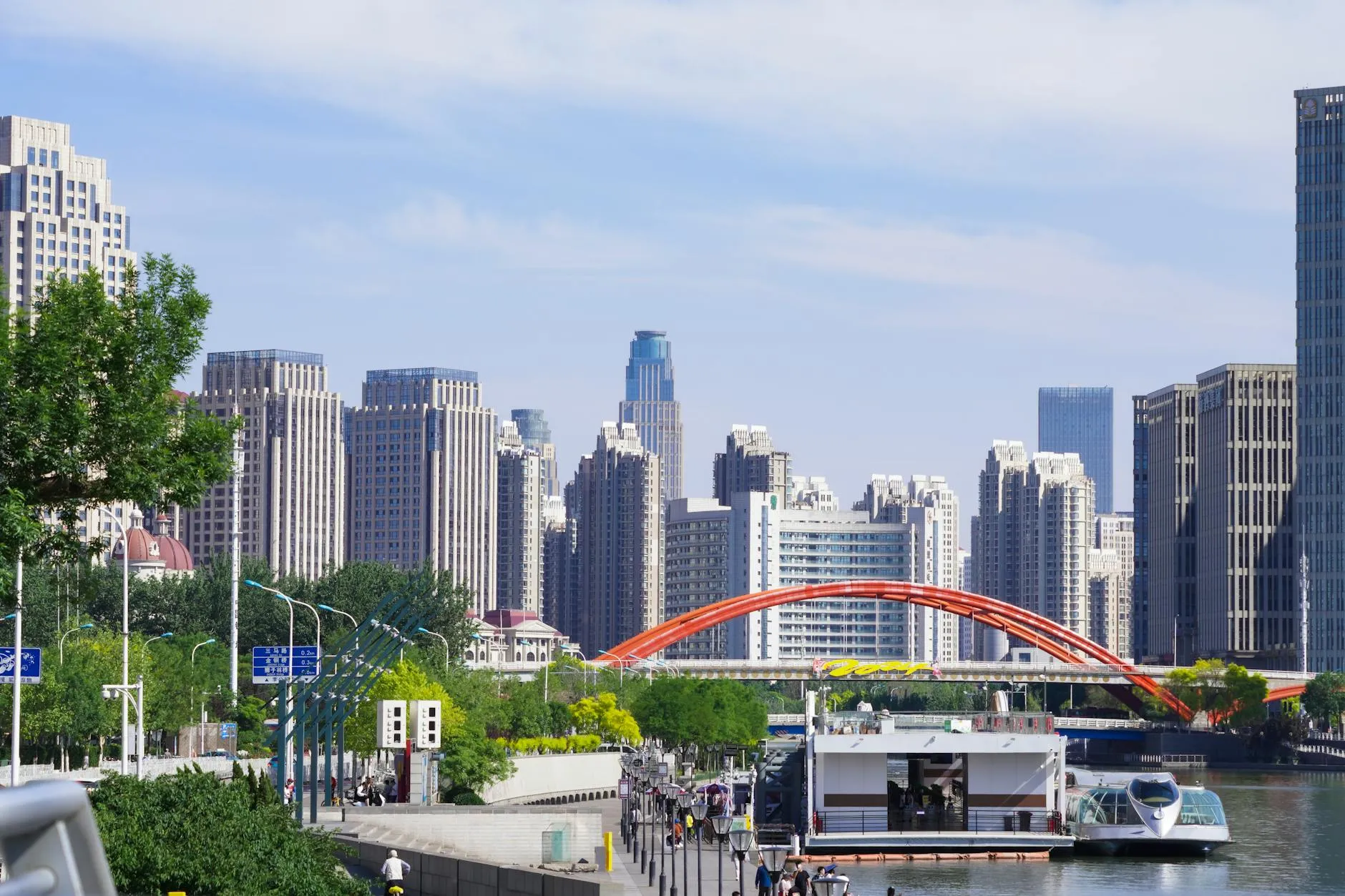 Tianjin, China — Stunning view of Tianjin skyline featuring skyscrapers and the Haihe River with a prominent orange bridge.