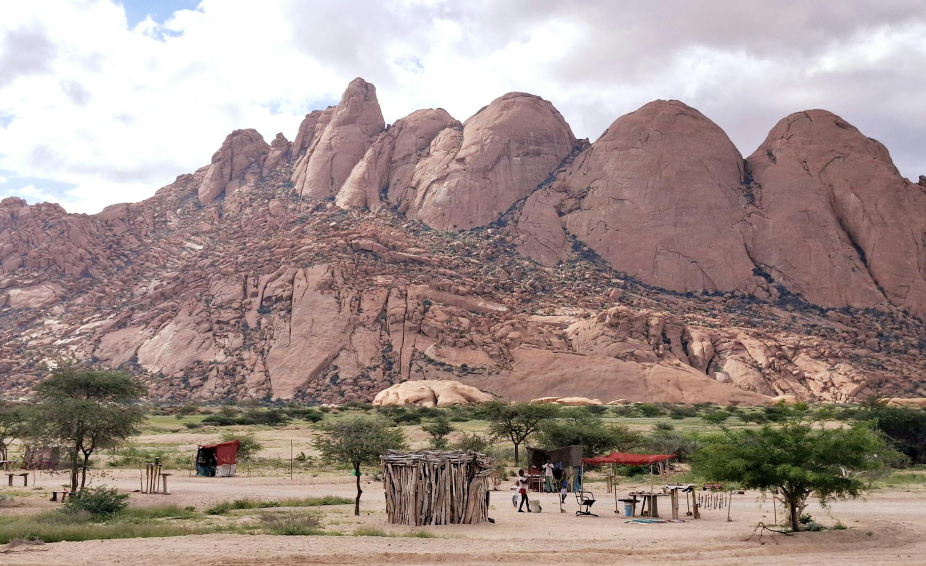 Windhoek Namibia — Dramatic landscape of the Spitzkoppe mountains with traditional huts and vegetation in arid Namibia.