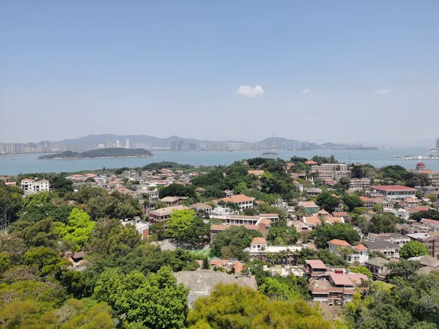 Stunning aerial view of Xiamen, showcasing lush greenery and coastal buildings under a clear sky.