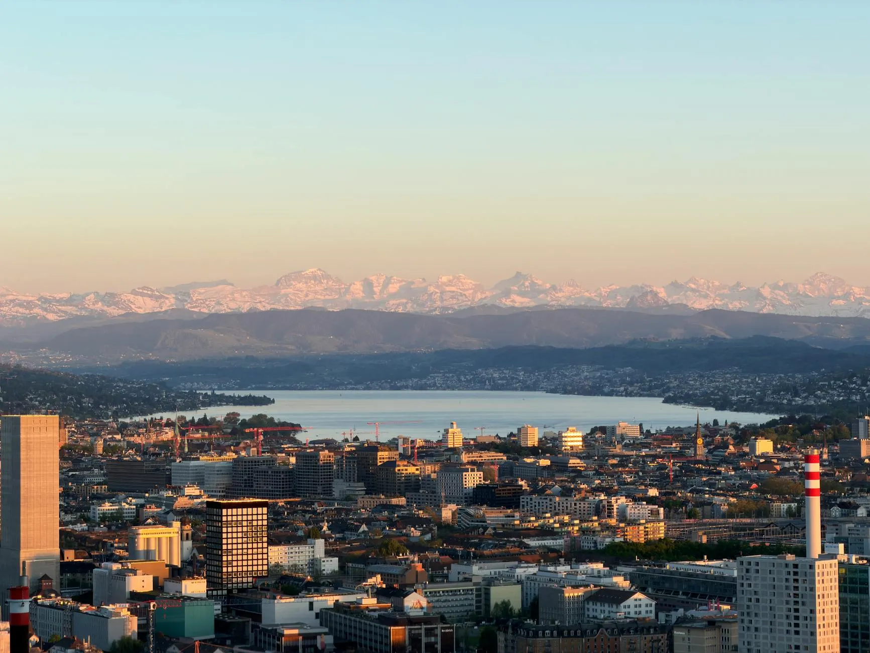 Stunning aerial view of Zürich cityscape with Lake Zürich and the Alps in the background.
