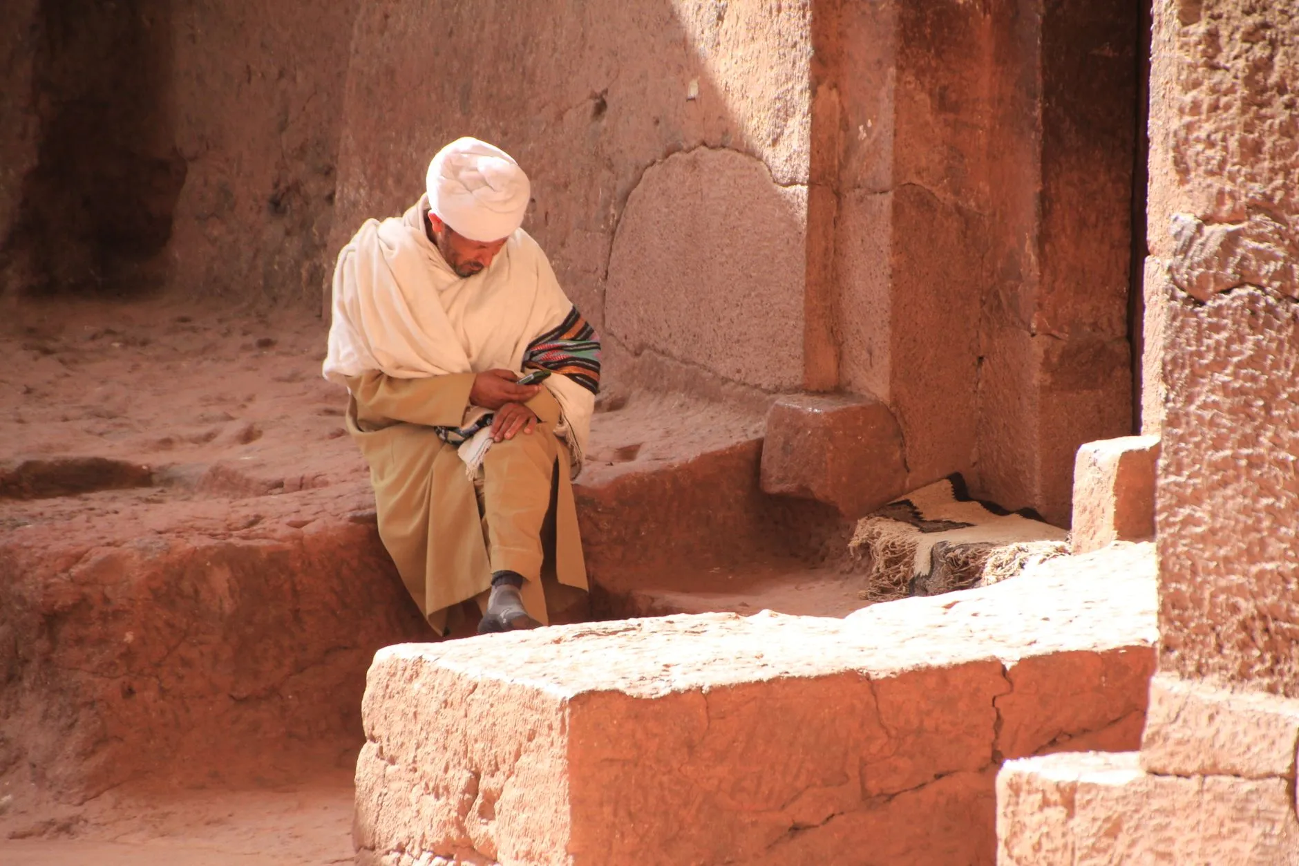 Ethiopia — A man in traditional attire sitting within the ancient rock-hewn churches of Lalibela, Ethiopia.