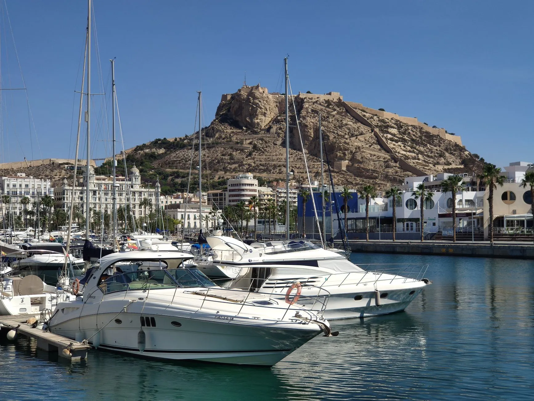 Alicante, Spain — Picturesque Alicante harbor with yachts and Santa Barbara Castle under sunny skies.