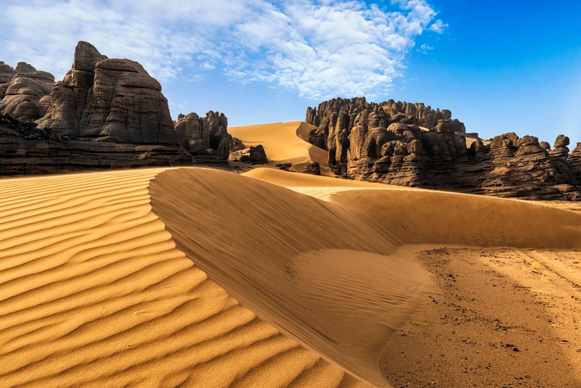 Algeria — Breathtaking view of sand dunes against rocky formations in Algeria's Sahara desert.