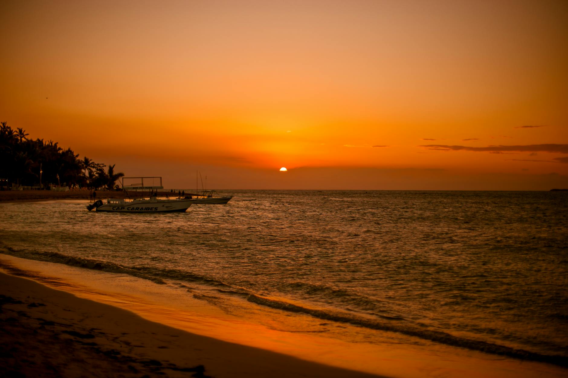 Samaná, Dominican Republic — Stunning sunset at Las Terrenas beach in Dominican Republic, featuring boats and a golden seascape.