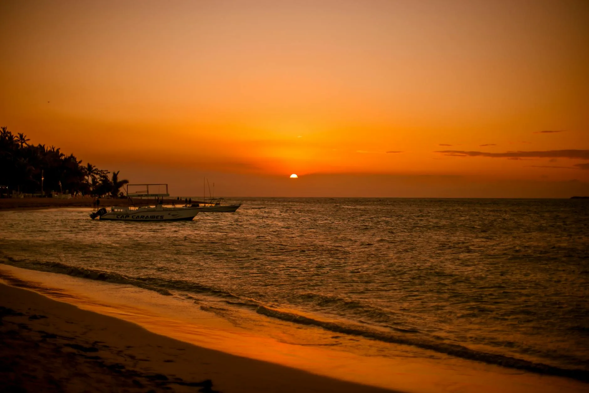 Samaná, Dominican Republic — Stunning sunset at Las Terrenas beach in Dominican Republic, featuring boats and a golden seascape.