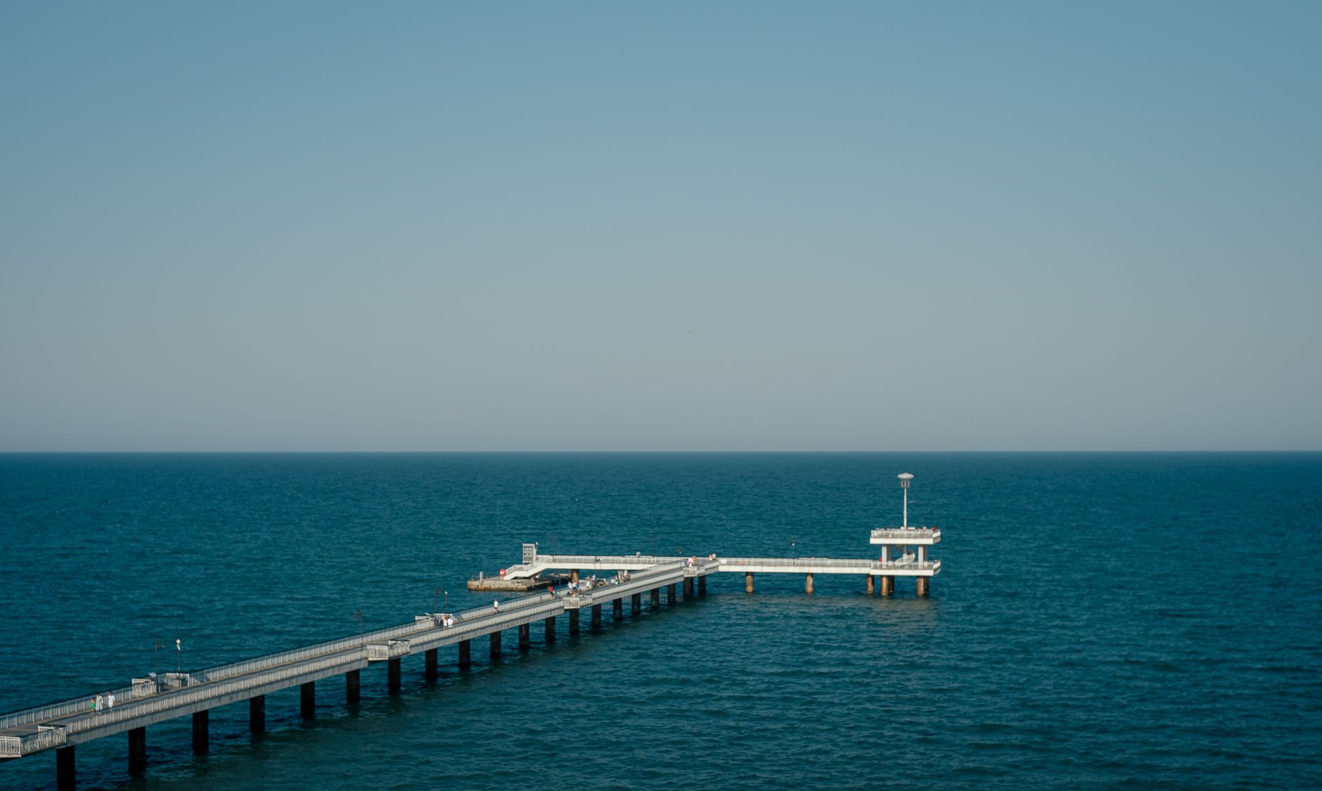 Burgas, Bulgaria — A tranquil view of the Burgas Pier reaching into the blue ocean under a clear sky.