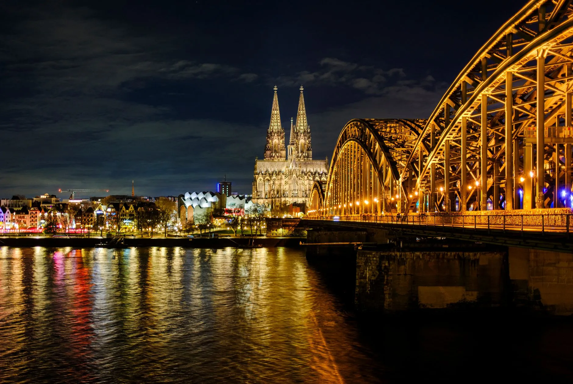 Cologne, Germany — A breathtaking night view of Cologne Cathedral and Hohenzollern Bridge over the Rhine River in Germany.