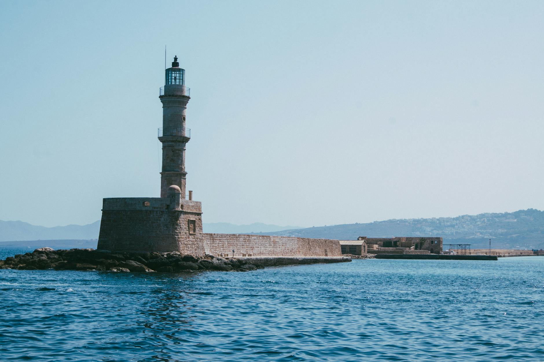 Chania, Crete — View of the iconic Chania Lighthouse and Venetian Harbor in Crete, Greece on a sunny day.