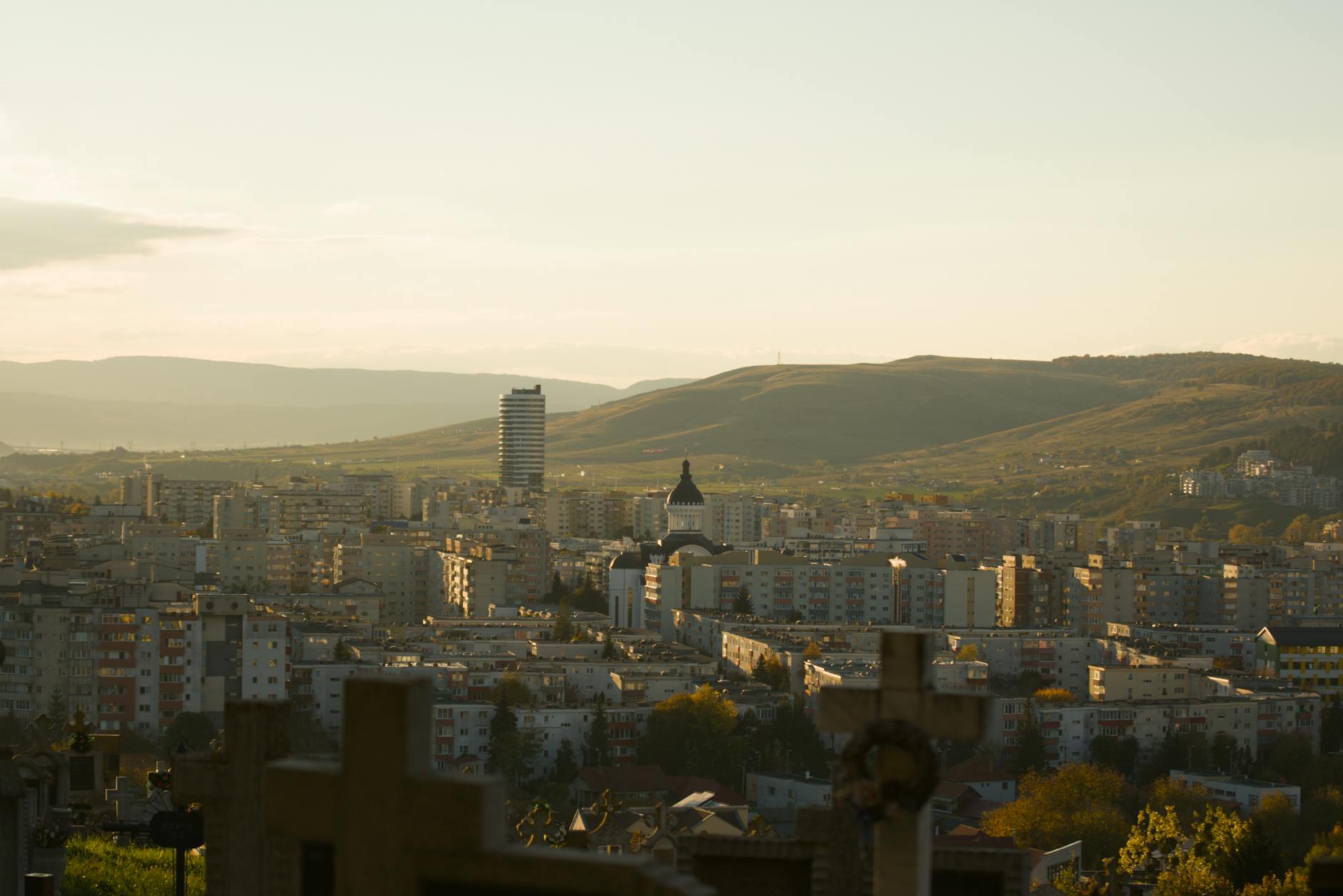 Cluj-Napoca, Romania — A scenic view of Cluj-Napoca city against the backdrop of rolling hills at sunset.