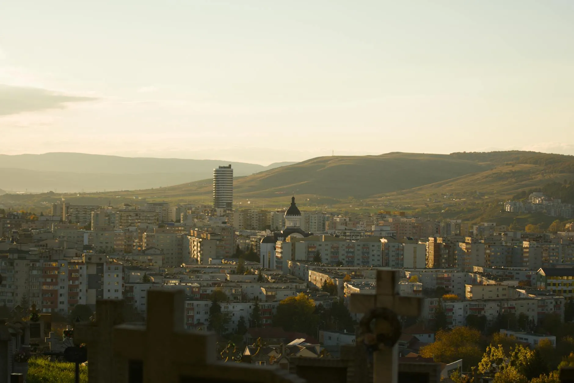 Cluj-Napoca, Romania — A scenic view of Cluj-Napoca city against the backdrop of rolling hills at sunset.