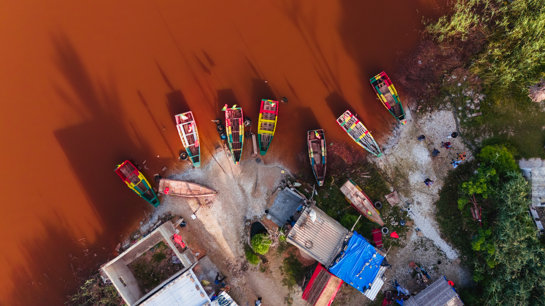 Senegal — Drone capture of colorful fishing boats moored on the edge of Lac Rose, Senegal.