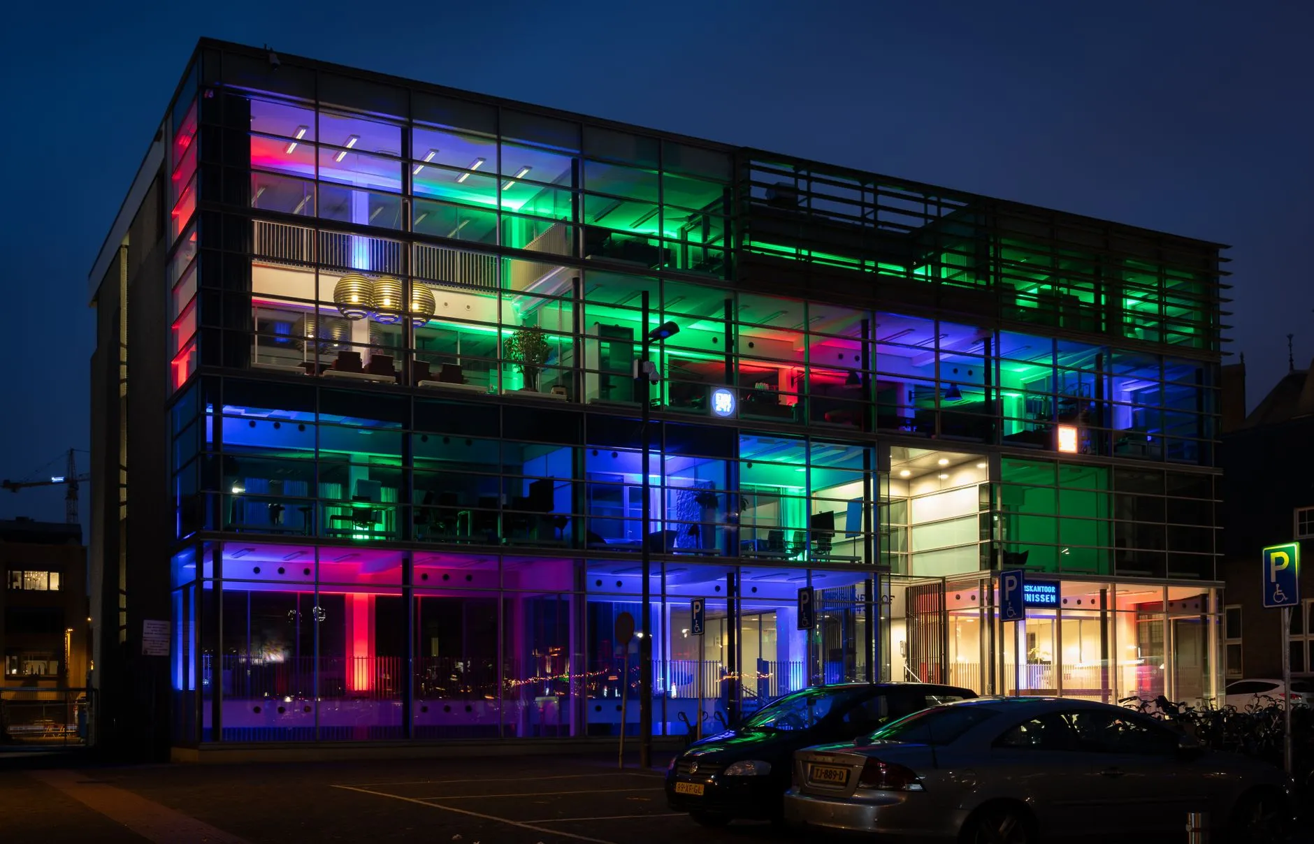 Eindhoven, Netherlands — Colorful lights illuminate a modern office building in Eindhoven at night.