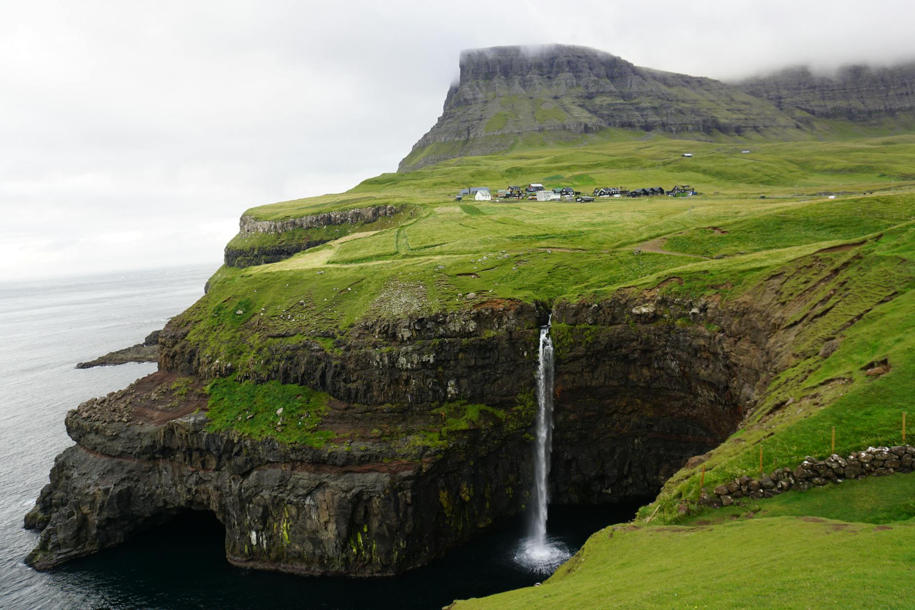 Vágar, Faroe Islands — Breathtaking view of Mulafossur waterfall cascading over green cliffs in the Faroe Islands.