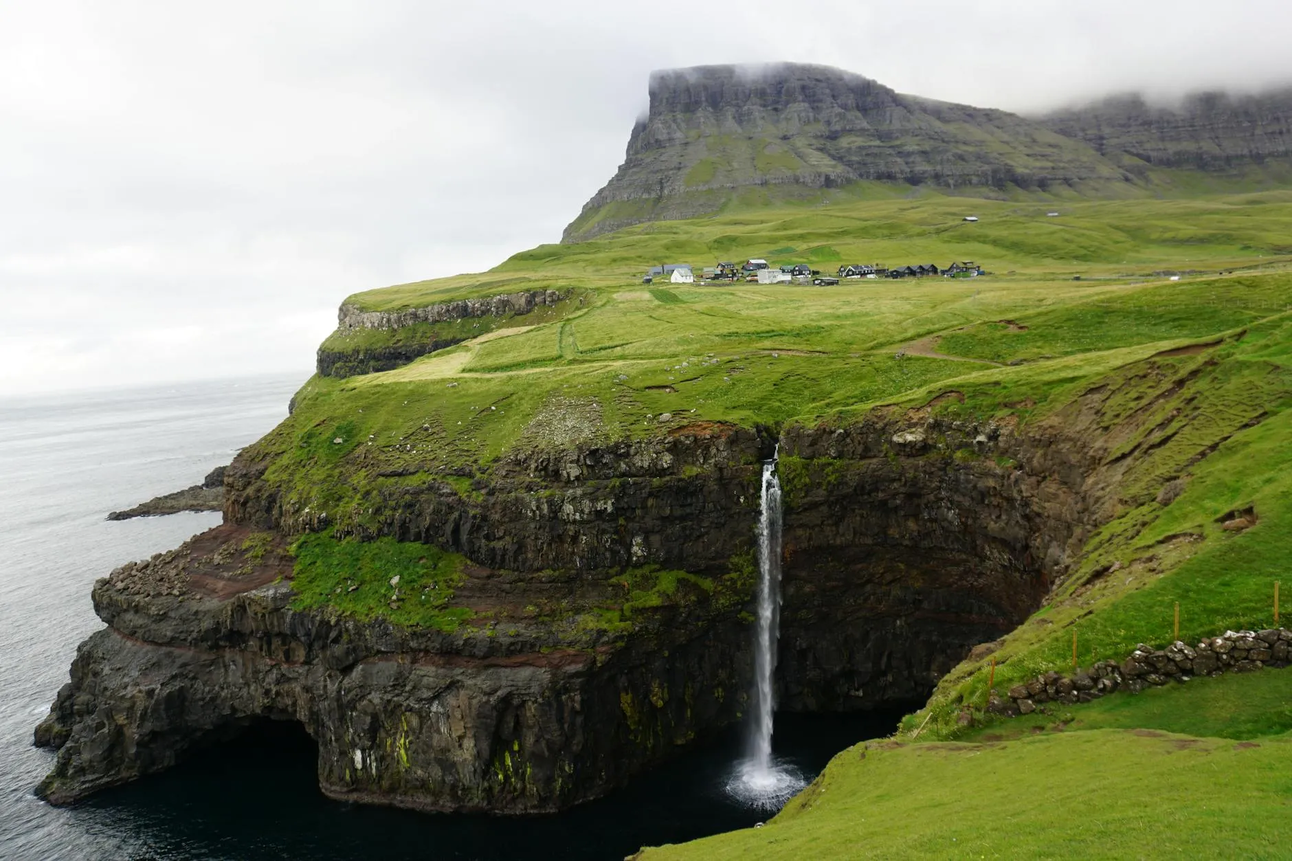 Vágar, Faroe Islands — Breathtaking view of Mulafossur waterfall cascading over green cliffs in the Faroe Islands.