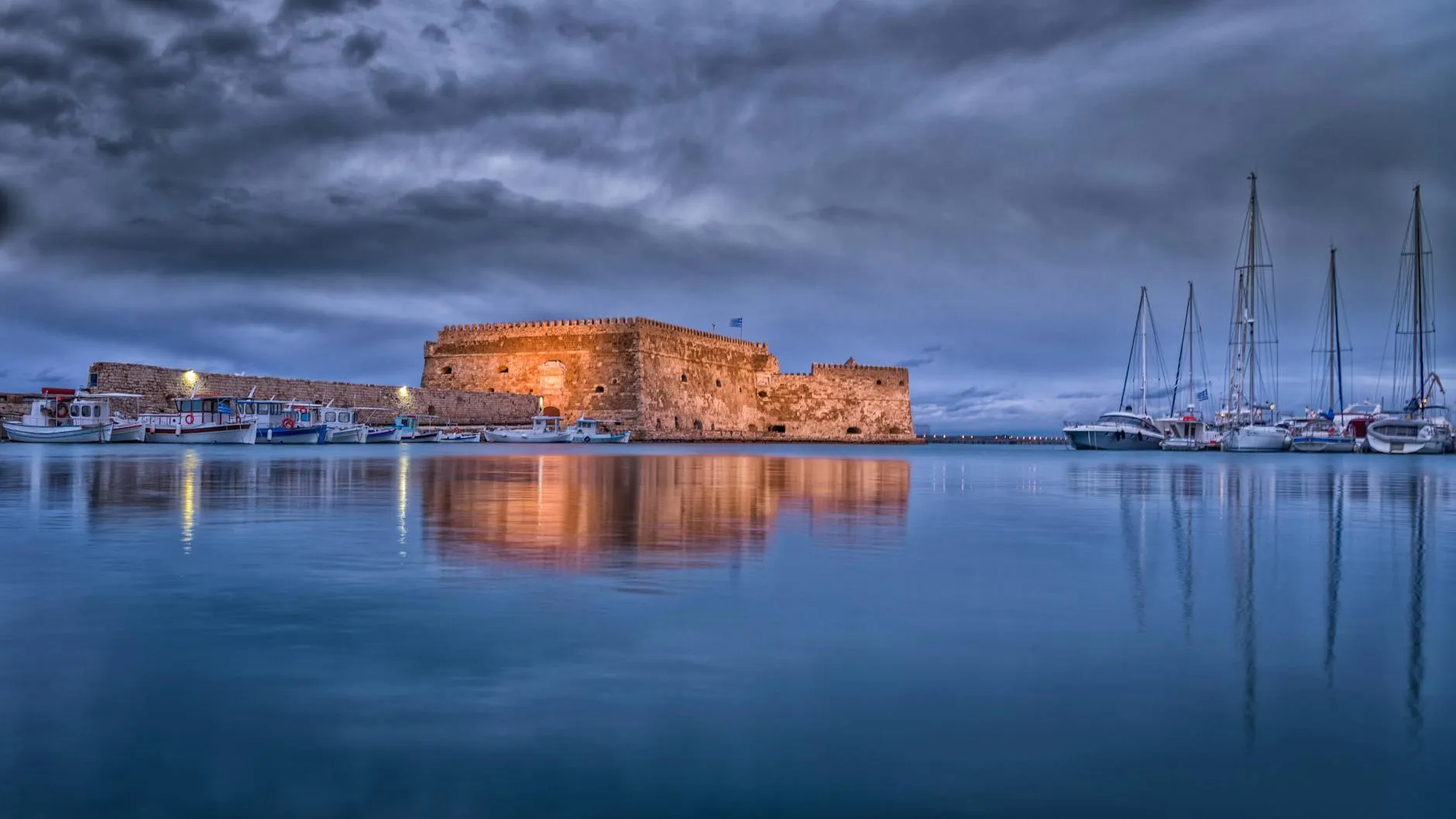 Heraklion, Crete — Majestic view of Koules Fortress reflected in calm waters at Heraklion harbor during twilight.