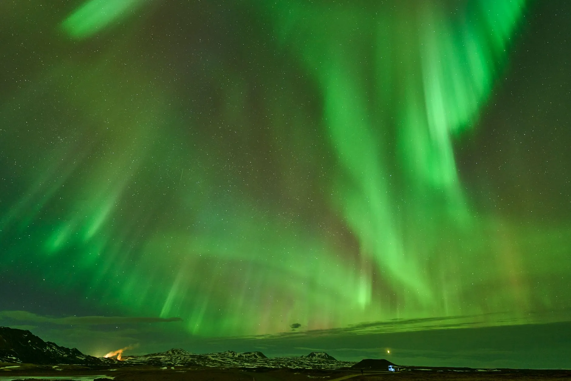 Iceland — Vivid aurora borealis lights up the night sky over a snowy Icelandic landscape.
