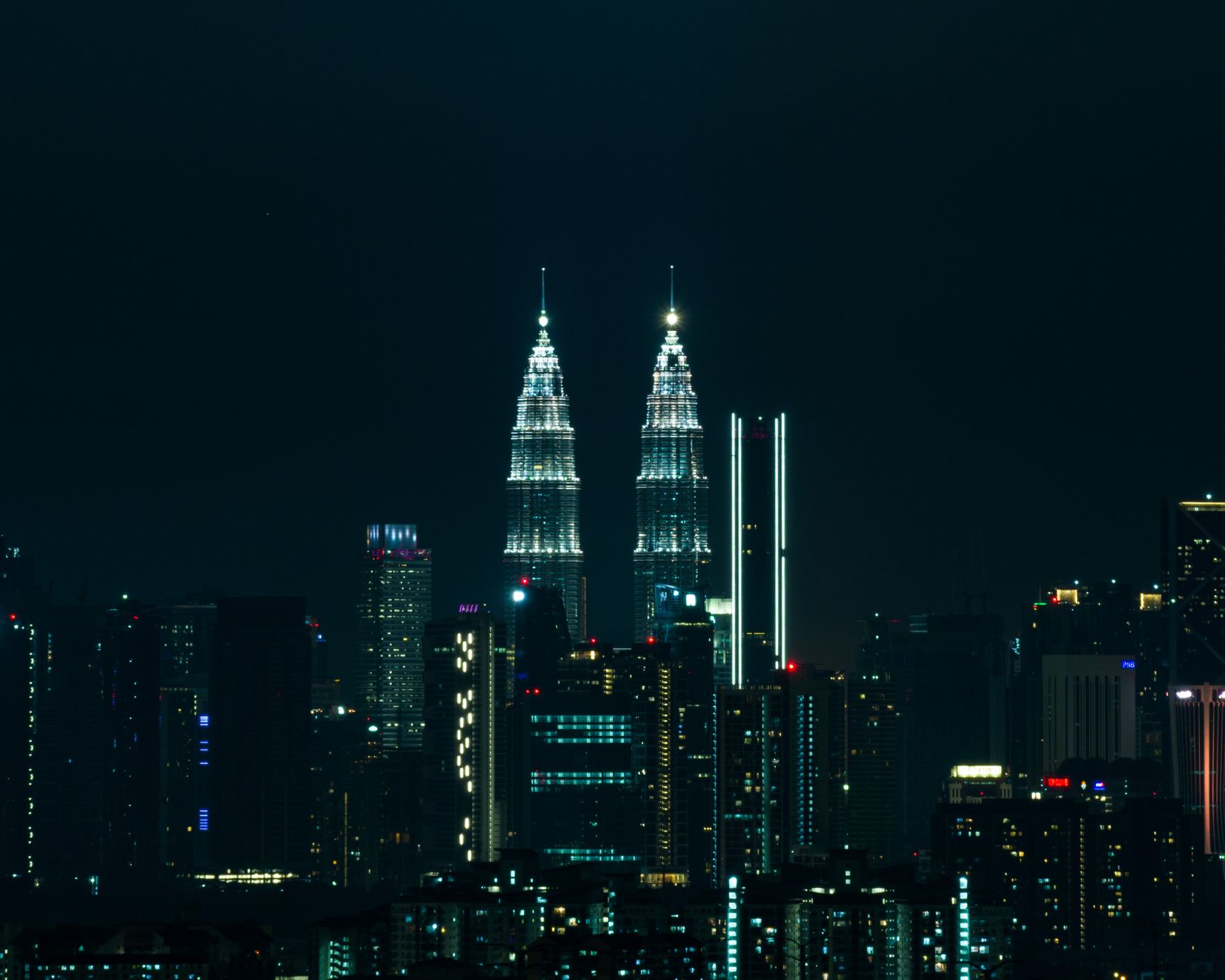 Malaysia — Breathtaking view of Kuala Lumpur's skyline at night featuring the iconic Petronas Towers illuminated against a dark sky.
