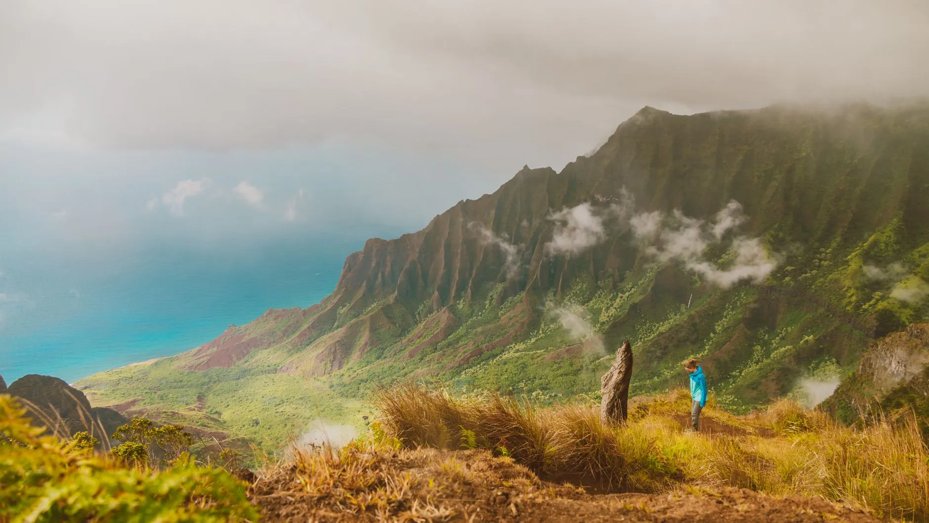 Kauai, Hawaii — Hiker gazing over the misty Na Pali Coast in Kauai, Hawaii, capturing adventure and nature's beauty.
