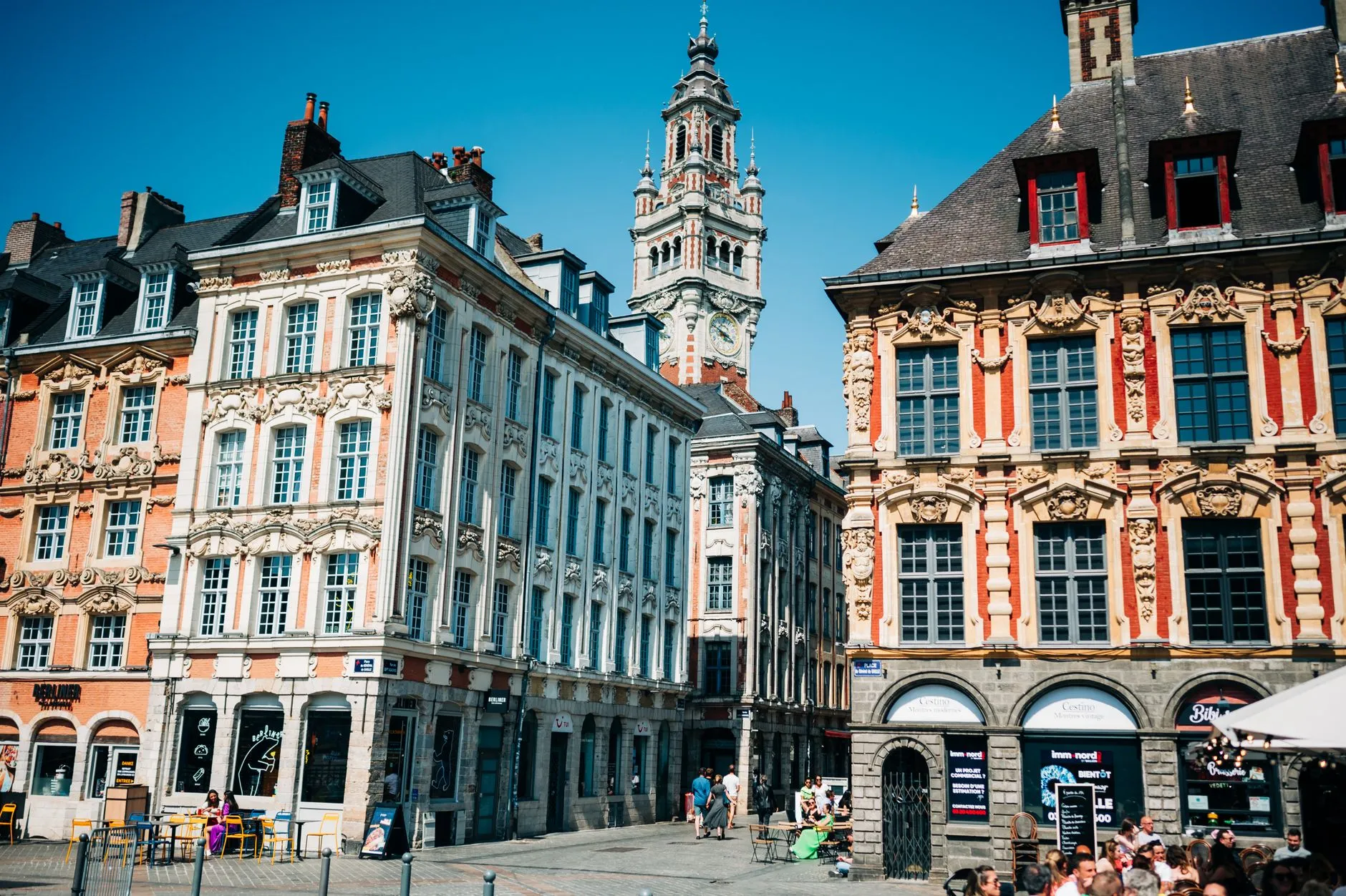 Lille, France — Ornate townhouses and belfry in Lille's Grand Place on a sunny day, showcasing local landmarks.