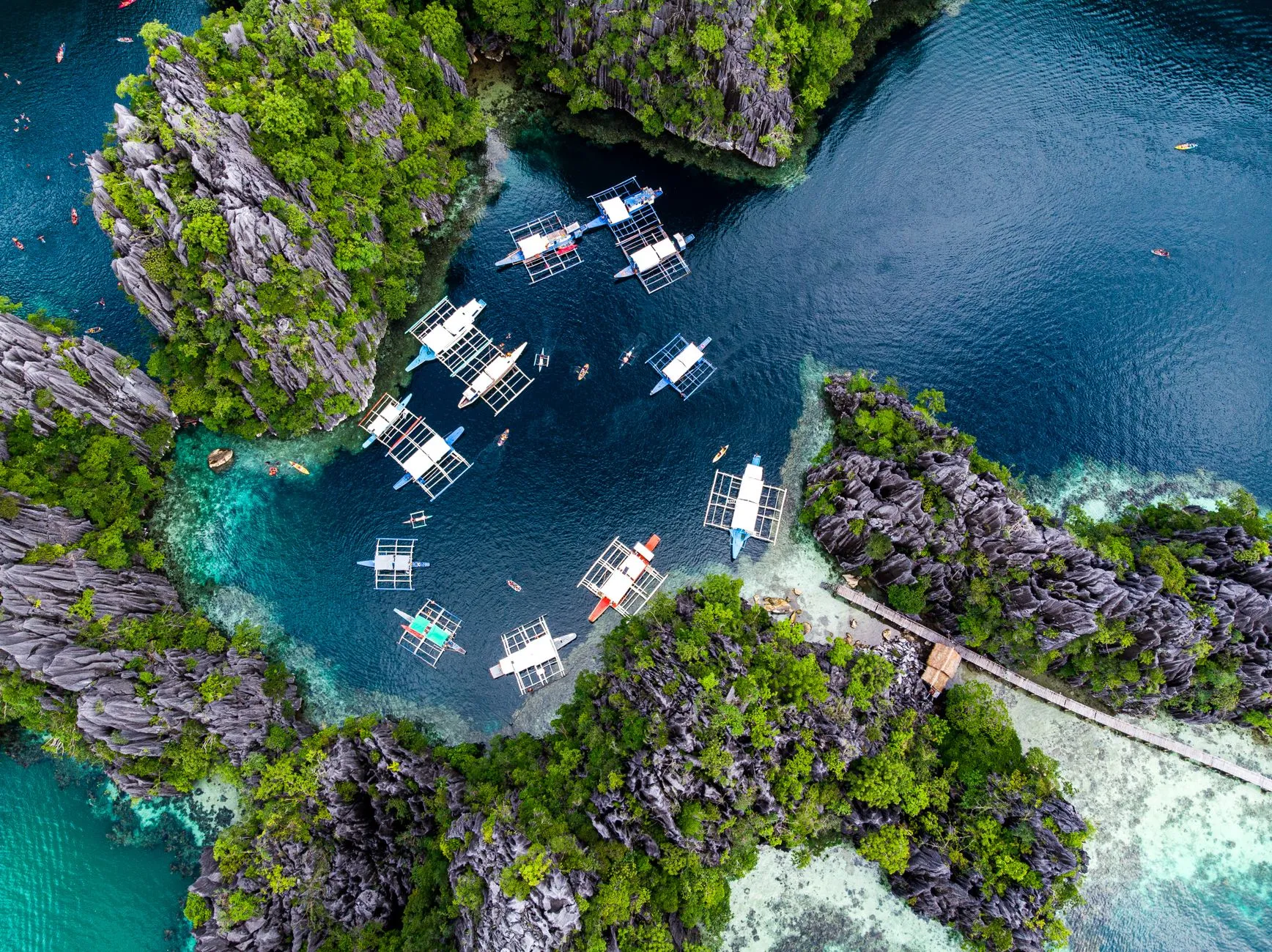 Palawan, the Philippines — outrigger bangka boats moored in a turquoise lagoon between limestone karst cliffs, the island trip most travellers connect on to from Manila