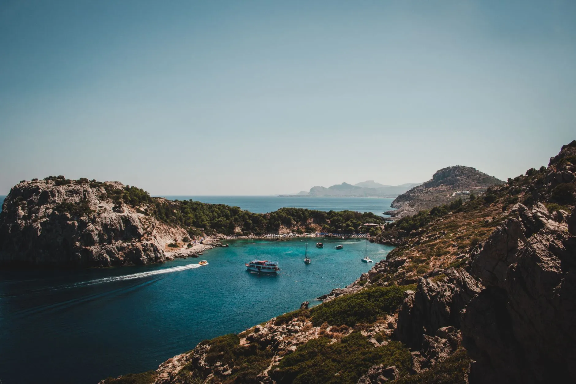 Rhodes, Greece — A breathtaking view of the crystal-clear waters of Lindos Bay surrounded by rocky cliffs in Rhodes, Greece.