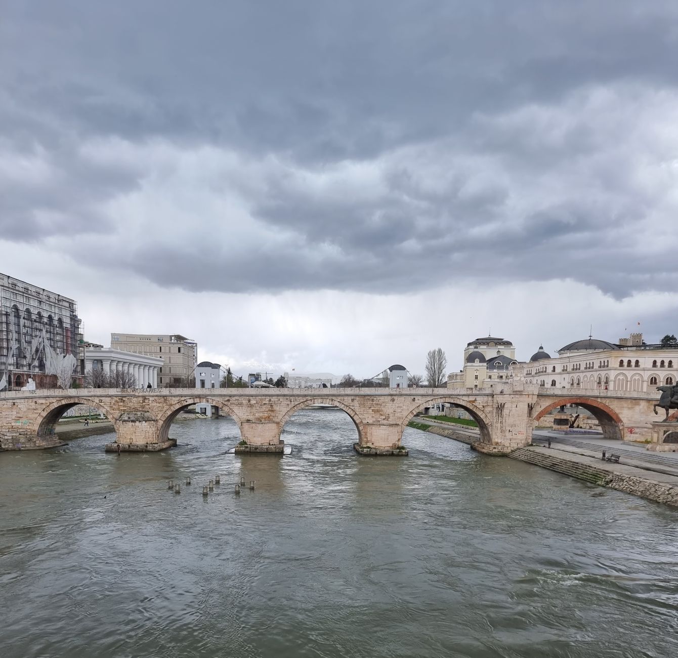 Skopje, North Macedonia — A scenic view of the historic Stone Bridge spanning the Vardar River under a cloudy sky in Skopje, North Macedonia.