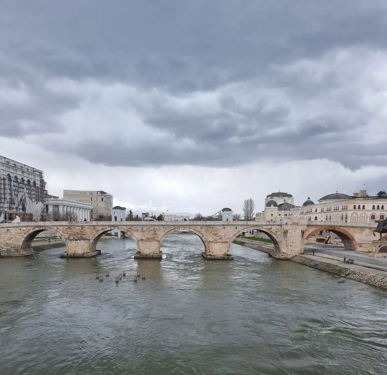 Skopje, North Macedonia — A scenic view of the historic Stone Bridge spanning the Vardar River under a cloudy sky in Skopje, North Macedonia.