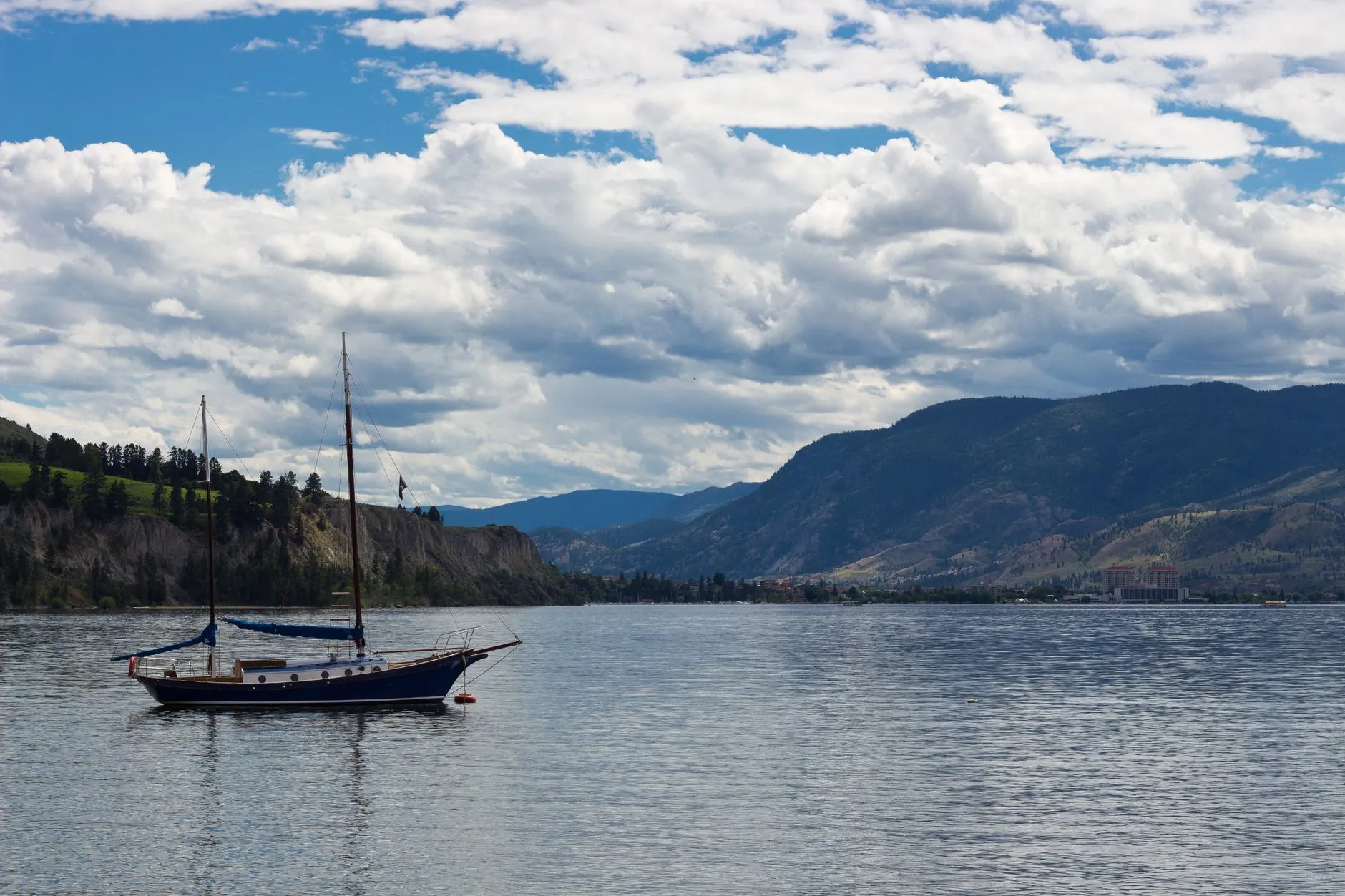 Kelowna, Okanagan — Peaceful scene with a boat on Okanagan Lake, surrounded by mountains and clouds in Kelowna, BC.