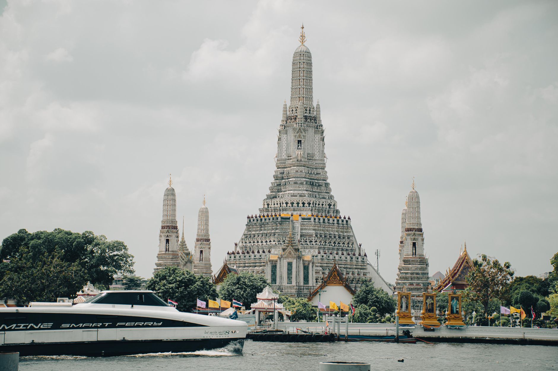 Stunning view of Wat Arun temple and Chao Phraya River in Bangkok, Thailand with a ferry boat.