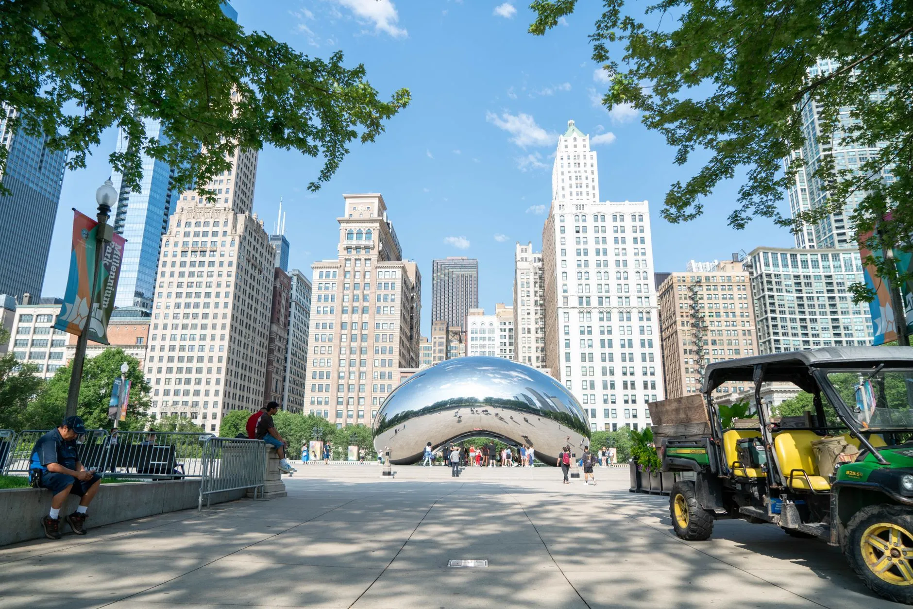 Cloud Gate sculpture in Chicago's Millennium Park with city skyline on a sunny day.