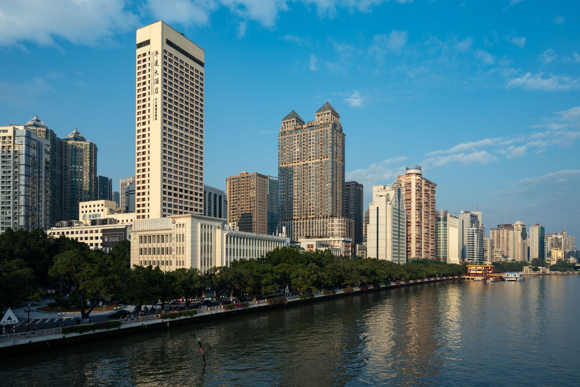 View of Guangzhou city skyline with skyscrapers along the Pearl River under a clear blue sky.
