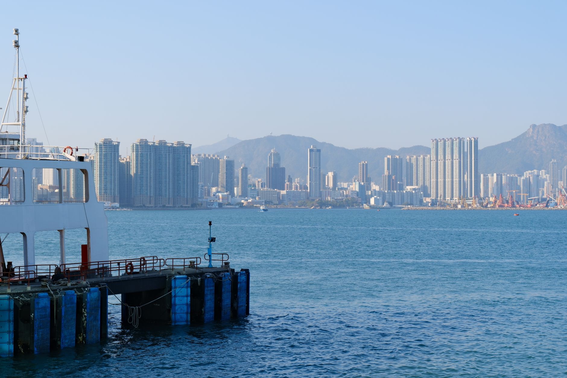 Skyline of Hong Kong with a ferry docked at the harbor, clear day view.