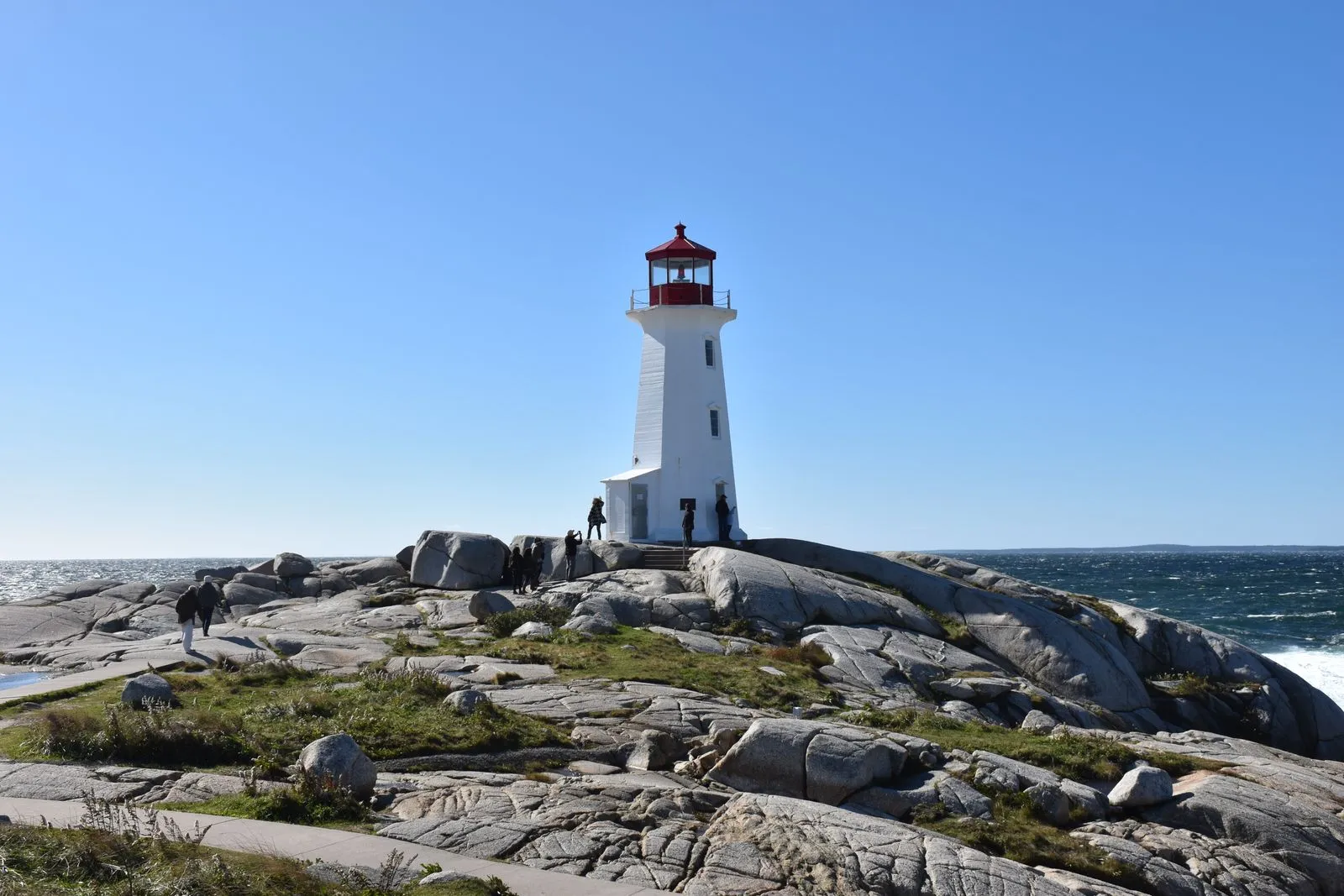 Peggy's Cove Lighthouse on the granite coast of Nova Scotia, Canada, under a clear blue sky beside the Atlantic