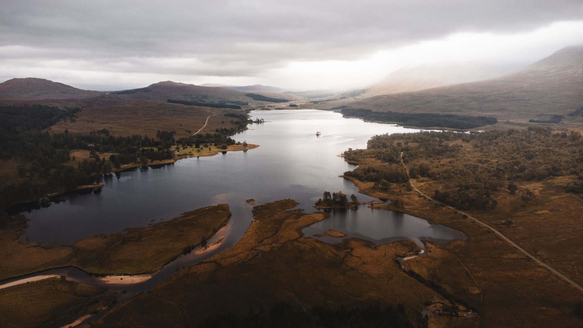 Aberdeen, Scotland — A dramatic aerial view of a loch surrounded by mountainous landscape in the Scottish Highlands.