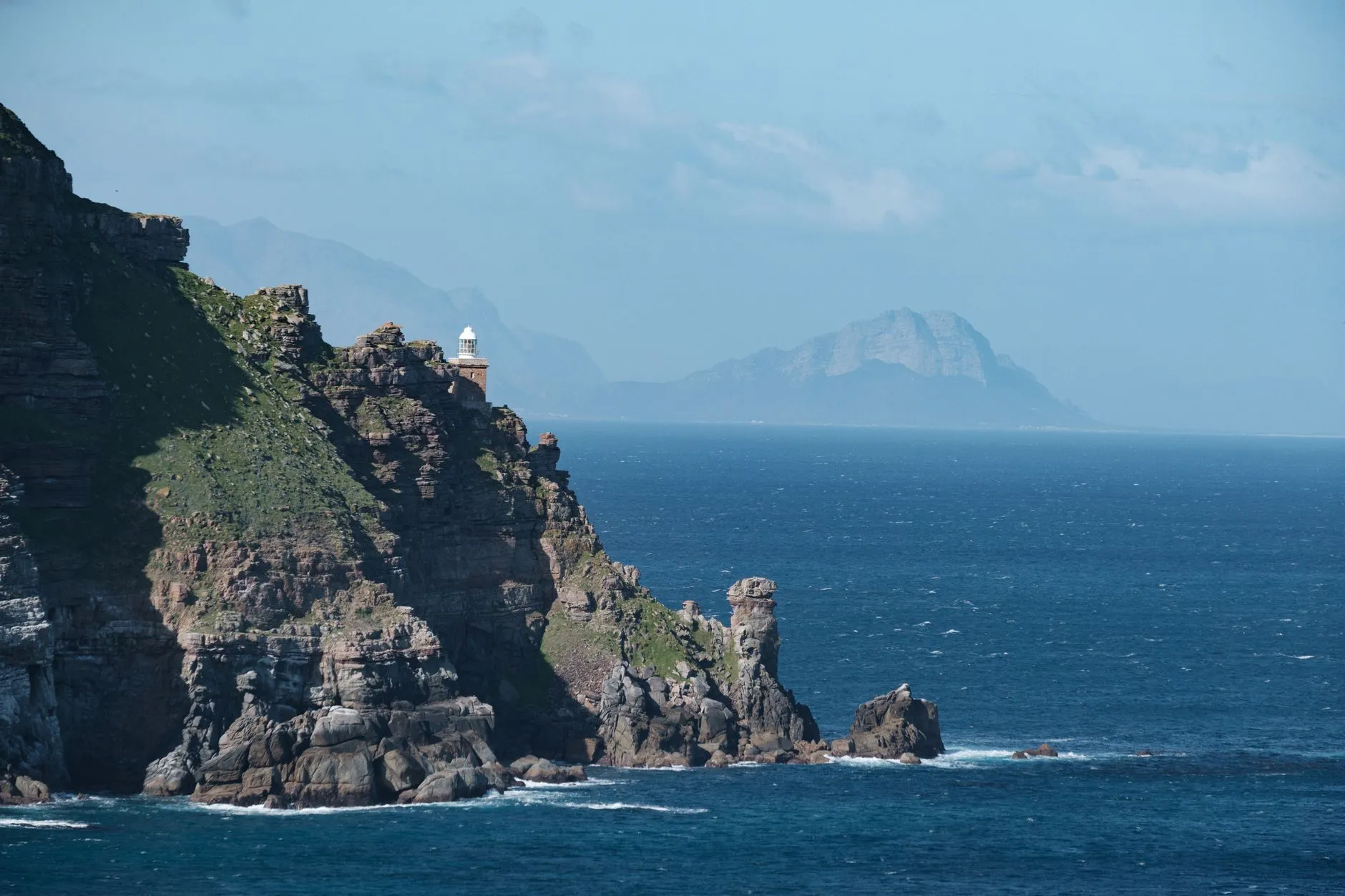 The cliffs and old lighthouse of Cape Point above the Atlantic Ocean, with the mountains across False Bay beyond, South Africa.