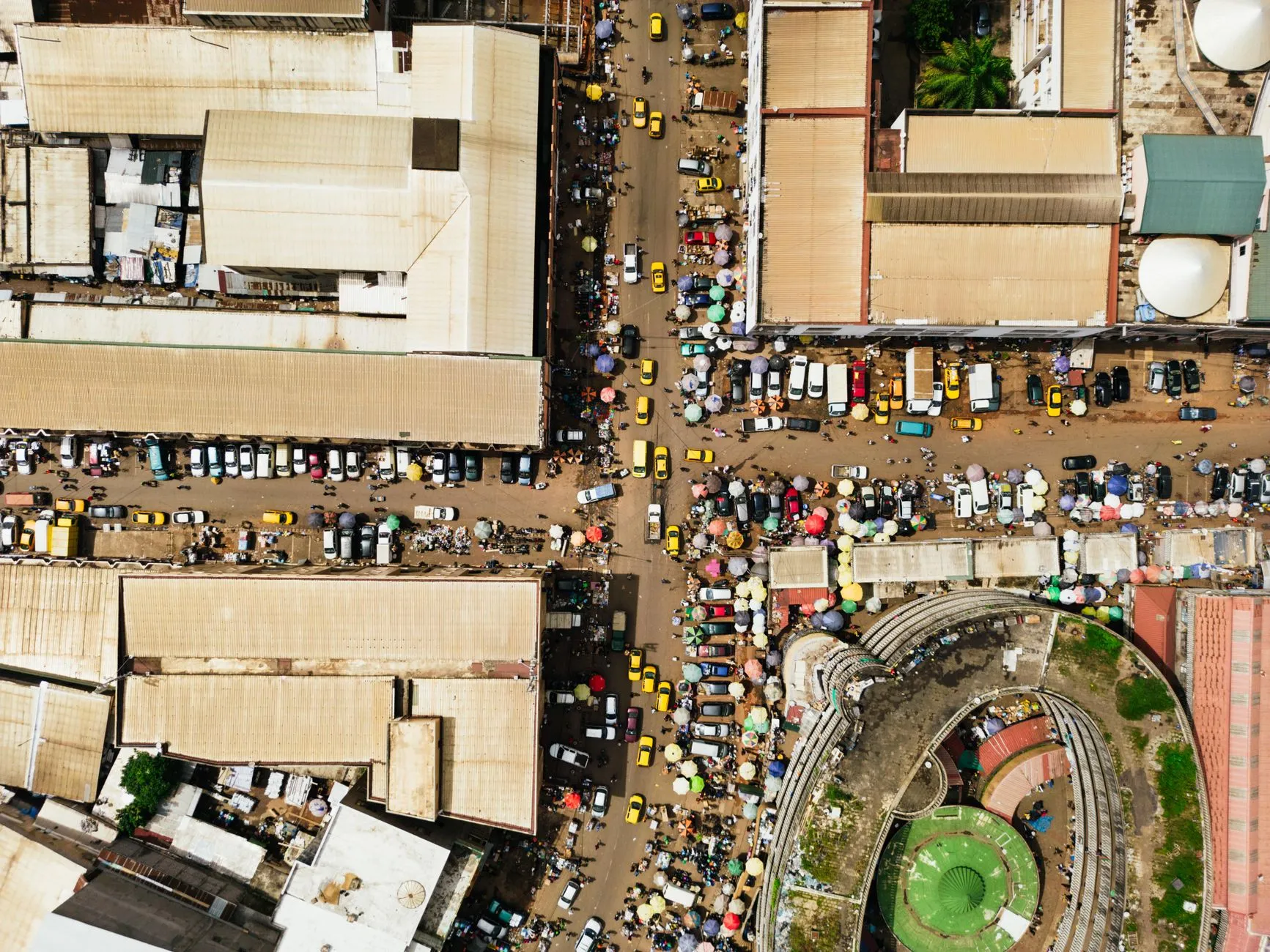 Cameroon — yellow taxis and market umbrellas on a city street from above
