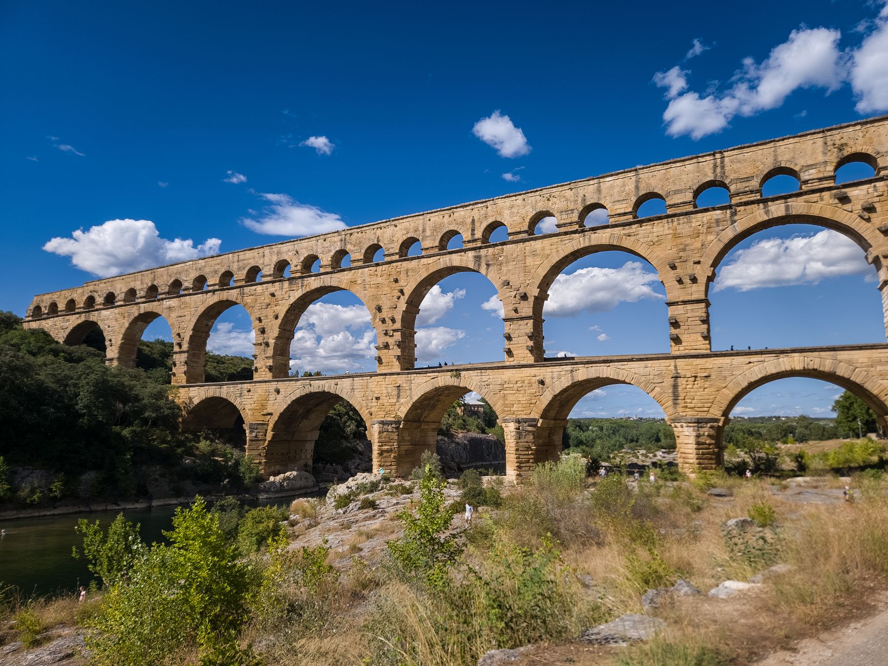 Nîmes, France — The Pont du Gard aqueduct, a Roman architectural marvel, against a clear blue sky in Nîmes, France.