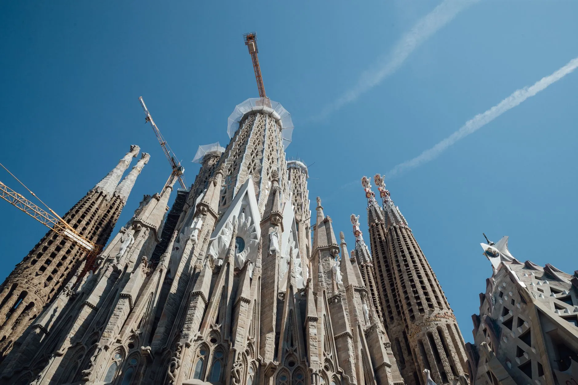 From below facade of tall ancient catholic Sagrada Familia temple with spires located in Barcelona in Spain in sunny weather